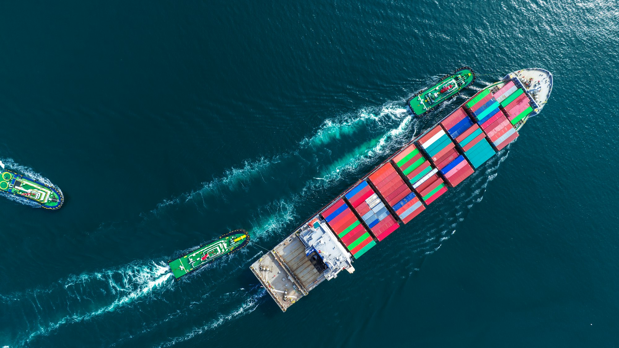 Aerial top view of cargo ship carrying container and running with tug boat for import export